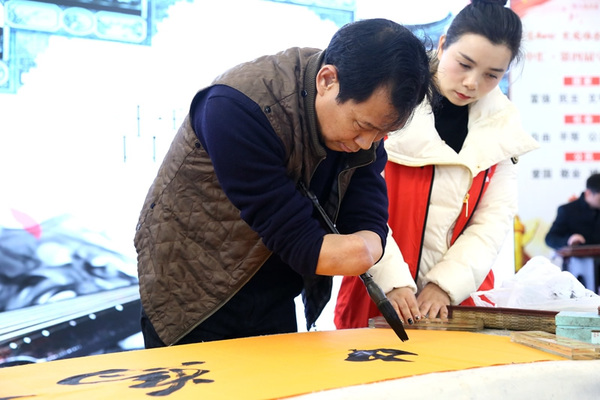 书法爱好者涂祖根(执笔者)现场表演书法.jpg
